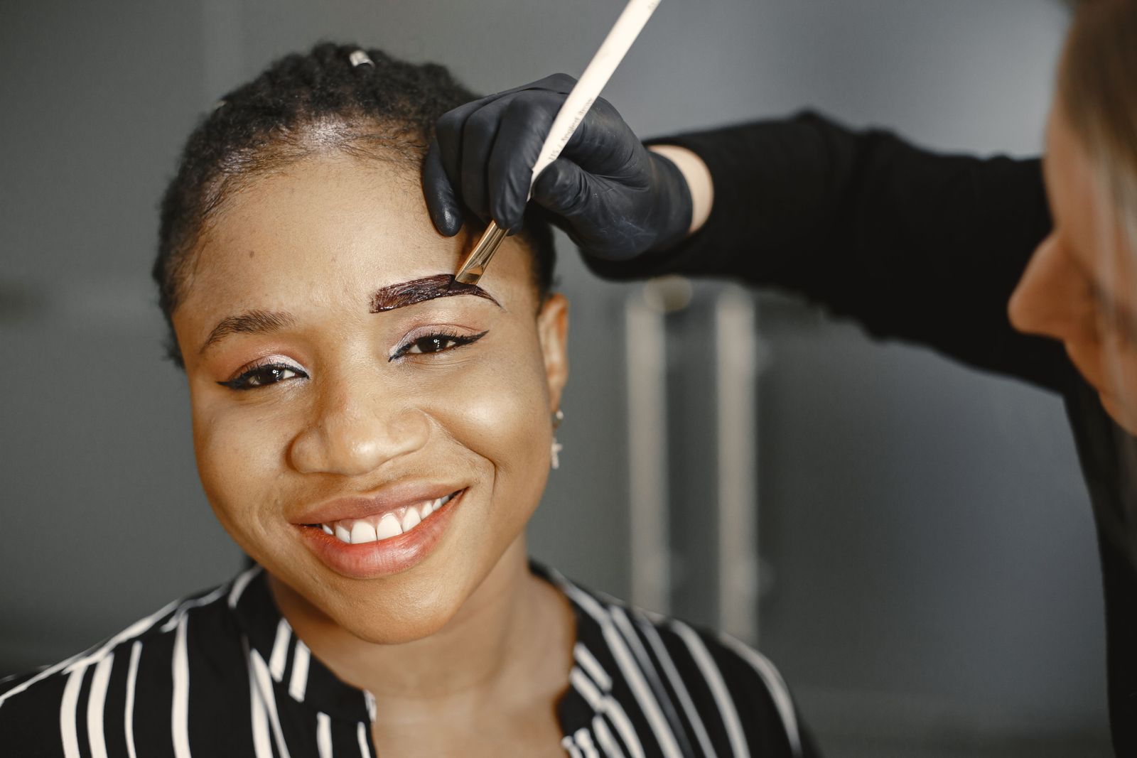 Smiling guest having her brows groomed during a lamination appointment