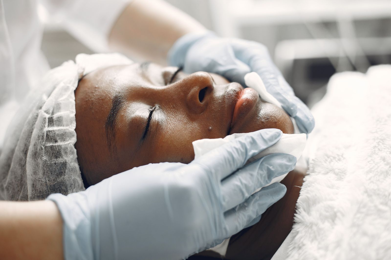 Gloved hands performing a gentle facial exfoliation treatment