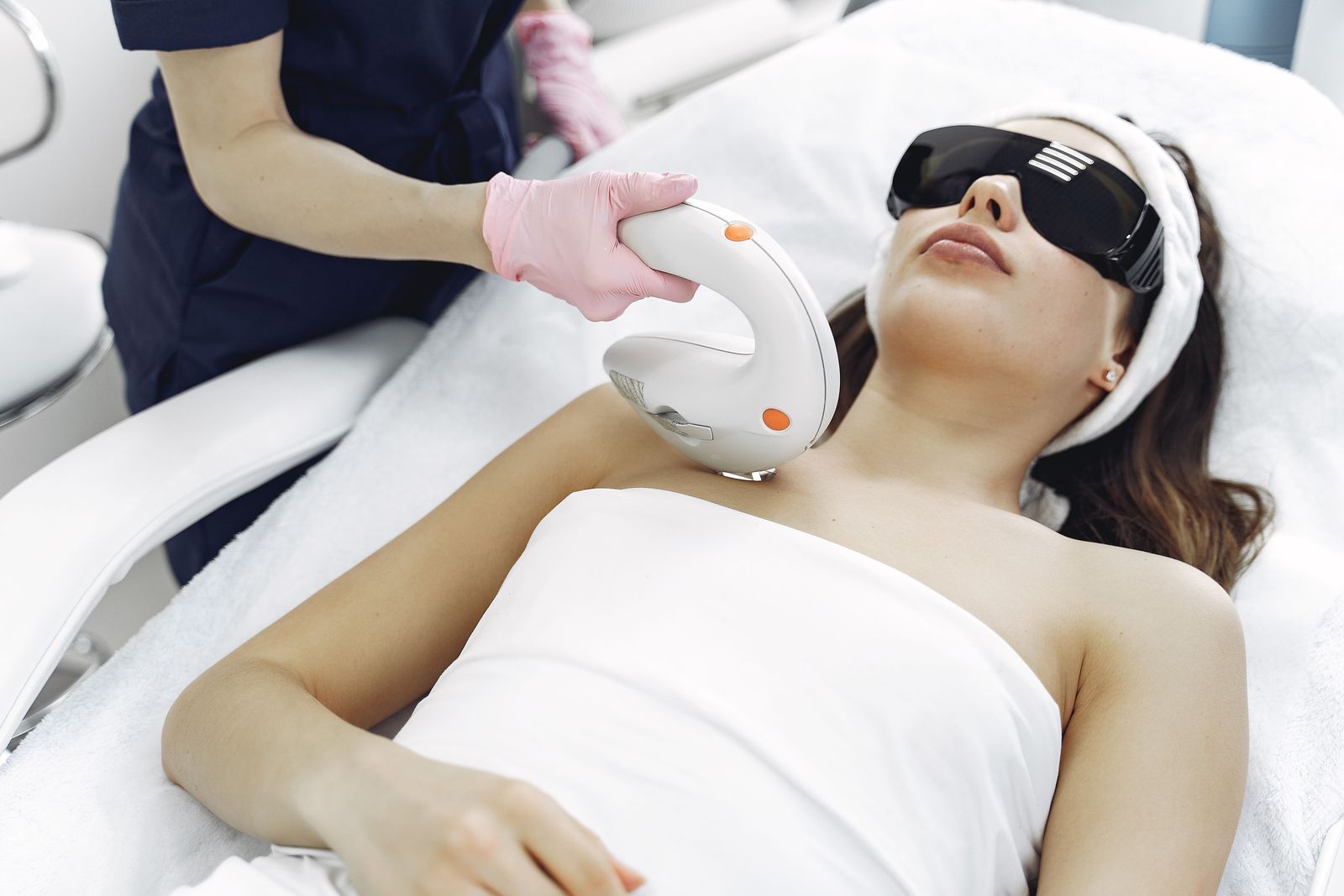 Guest wearing protective eye shields while an aesthetician treats her skin with an IPL handpiece
