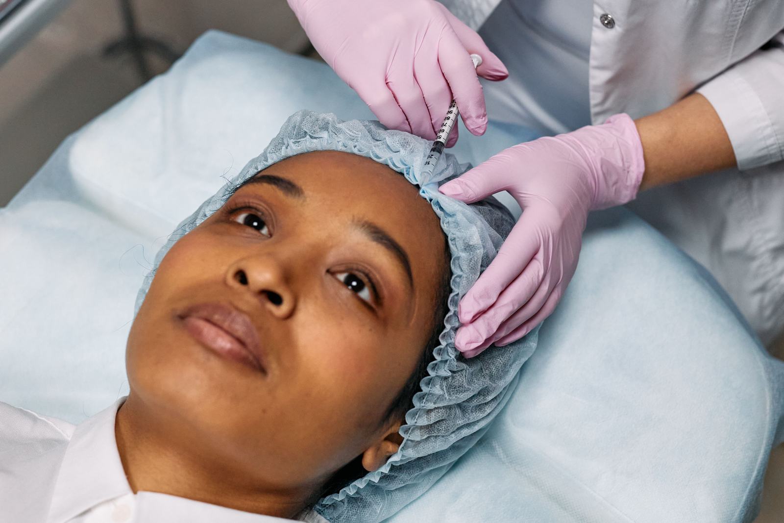 Person receiving a cosmetic forehead injection in a clinical treatment room