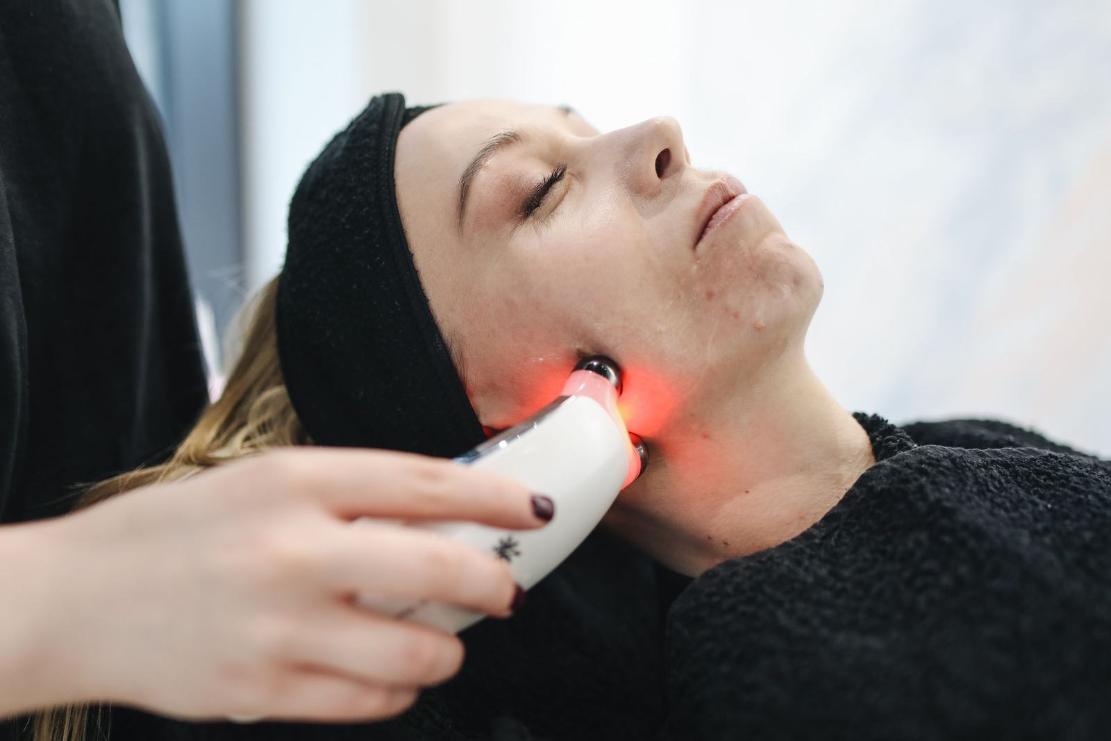 Woman receiving a handheld radiofrequency skin treatment along the jawline