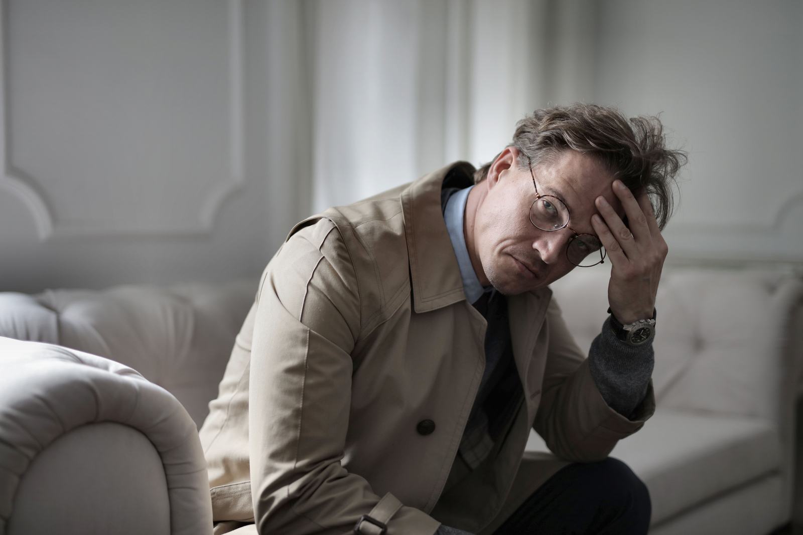 Man sitting on a couch looking tired and preoccupied
