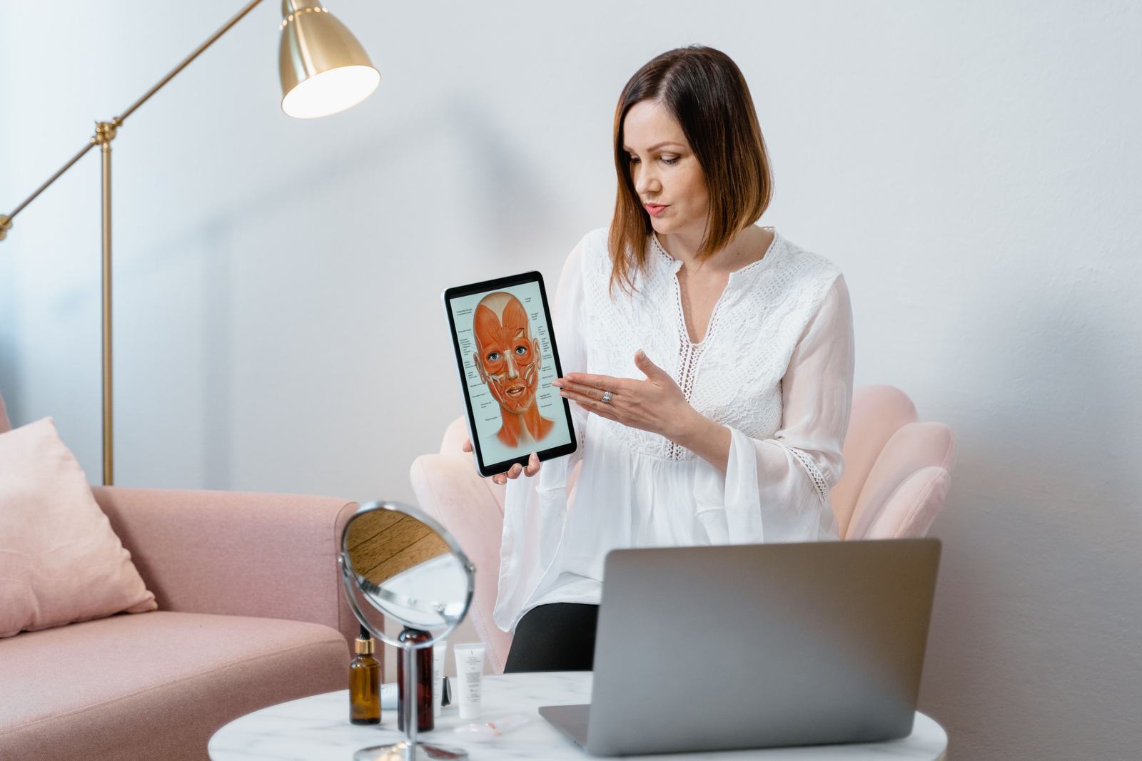 A woman holding a tablet that shows a diagram of the muscles of the face